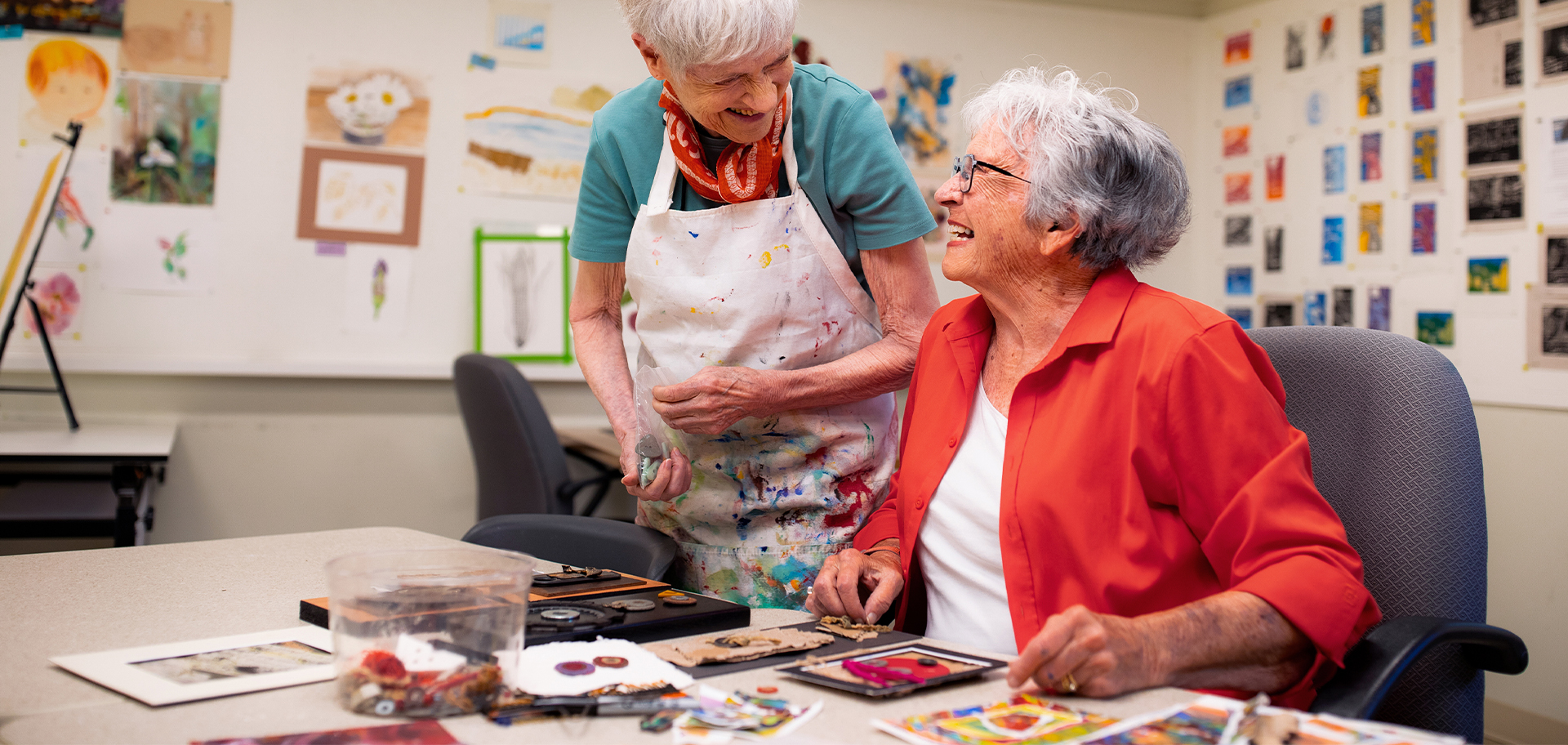 senior women talk while painting in the art room