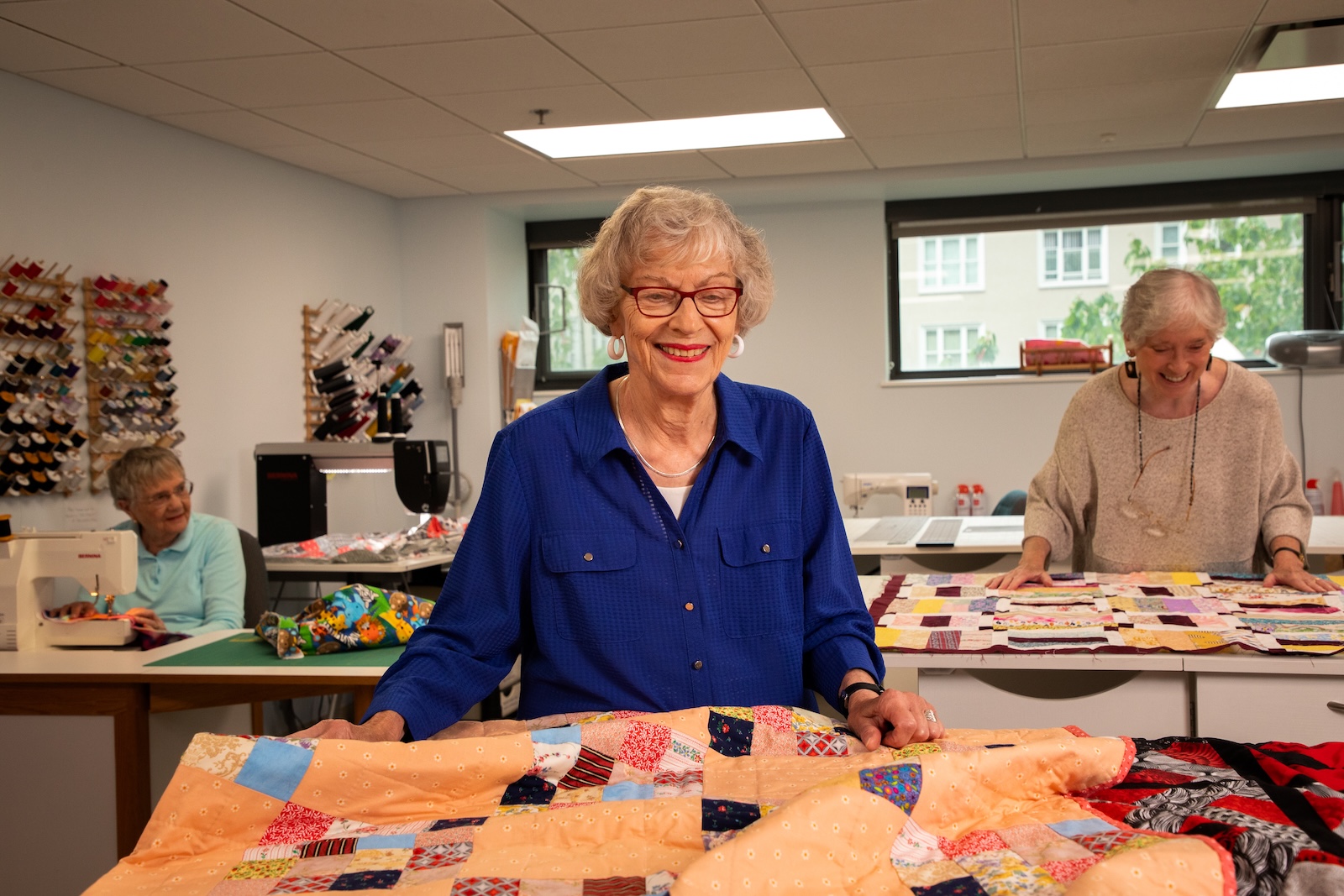 senior women smiling and sewing quilts